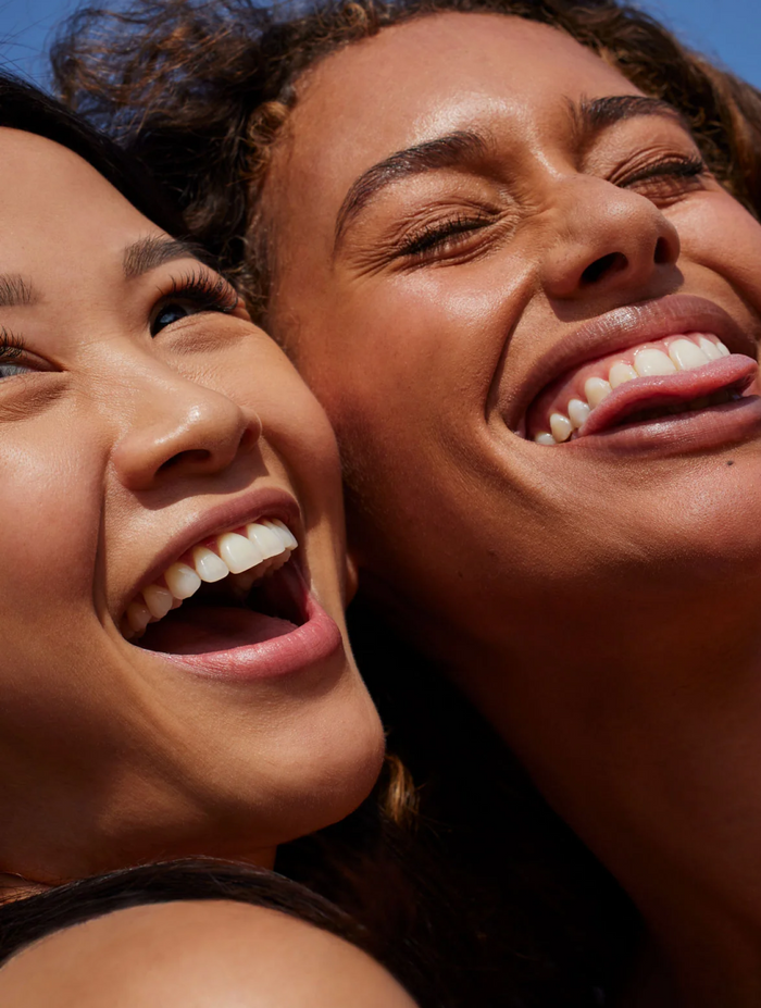 Two women laughing into the sun together