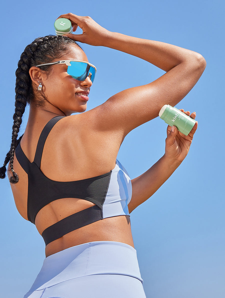 Woman wearing cycling glasses applies Kinfield All Star Anti-Chafe to her arm.