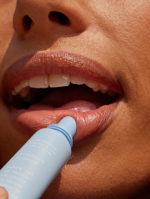 Close shot of woman's lips while she applies Kinfield Lip Rescue, a clear, hydrating balm.